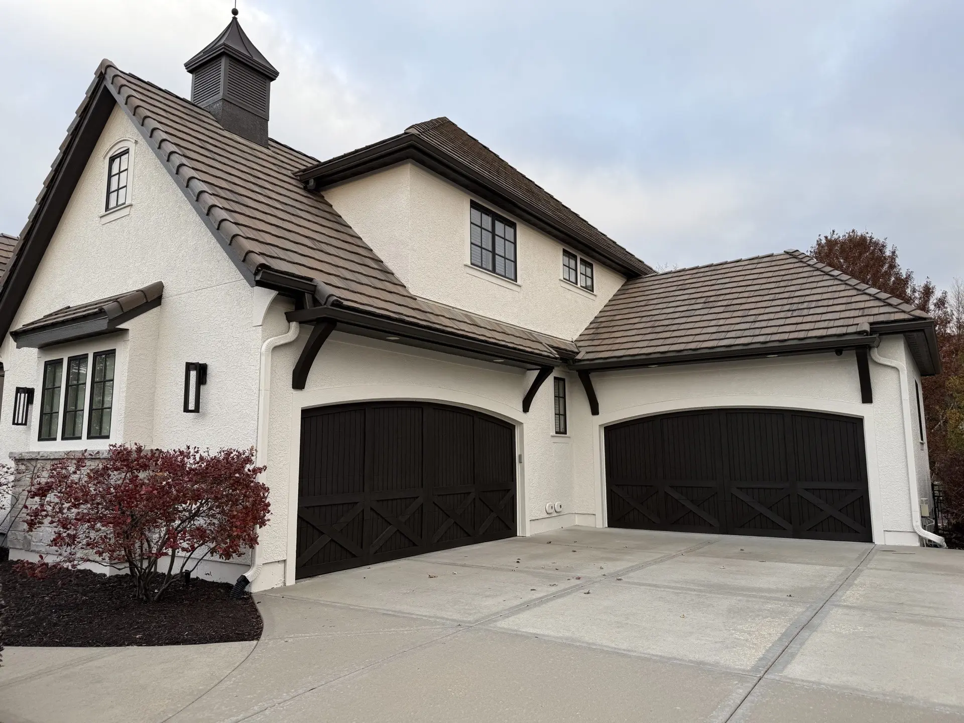 White stucco home with dark-stained garage doors painted by Catalyst Painting